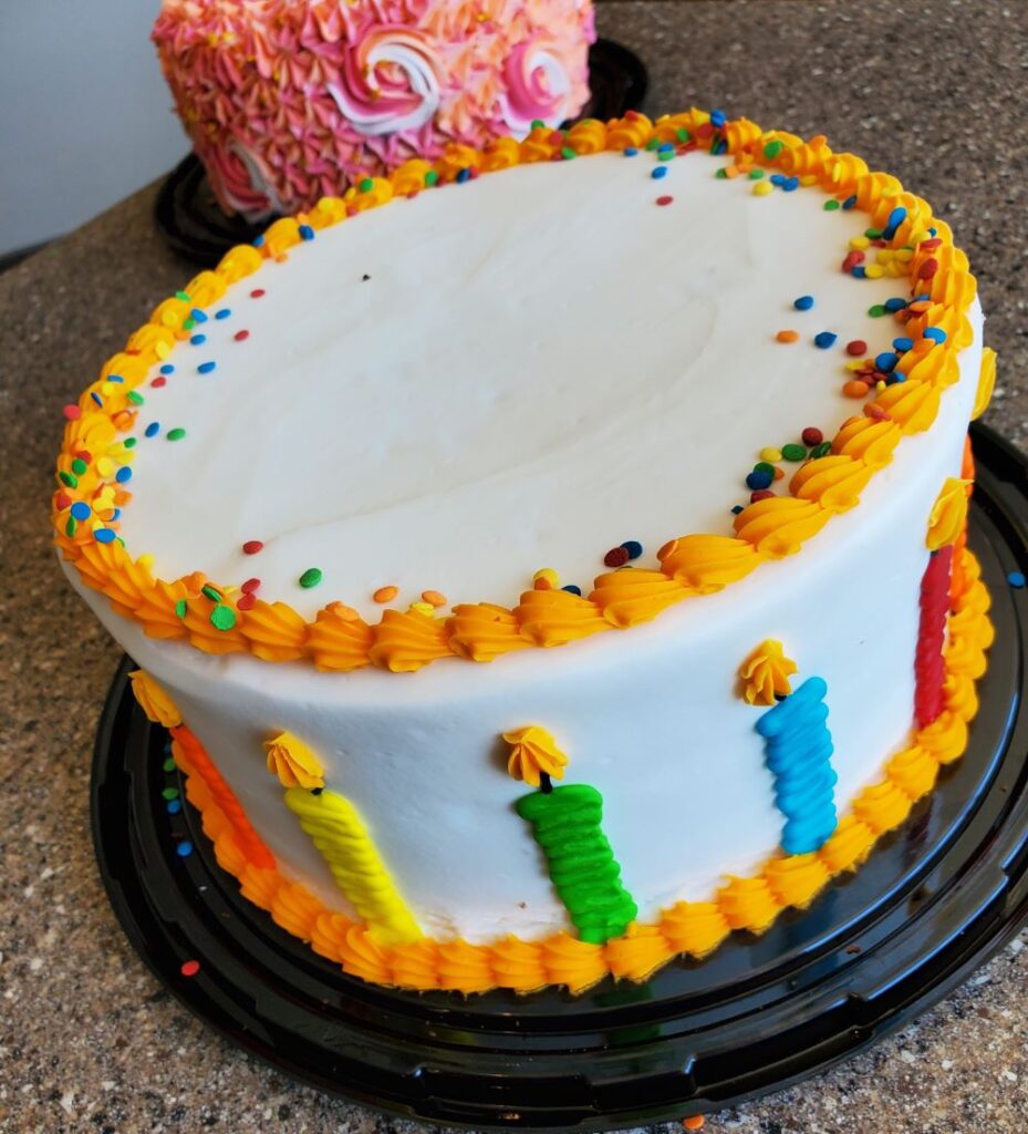 tiered frosted cake with frosted candles on the side of the cake