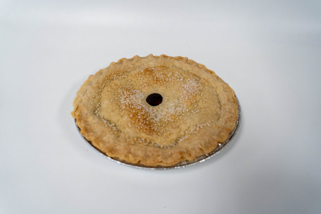 Cherry Pie with a smooth, golden top crust and rich, glossy cherry filling peeking through steam slits.