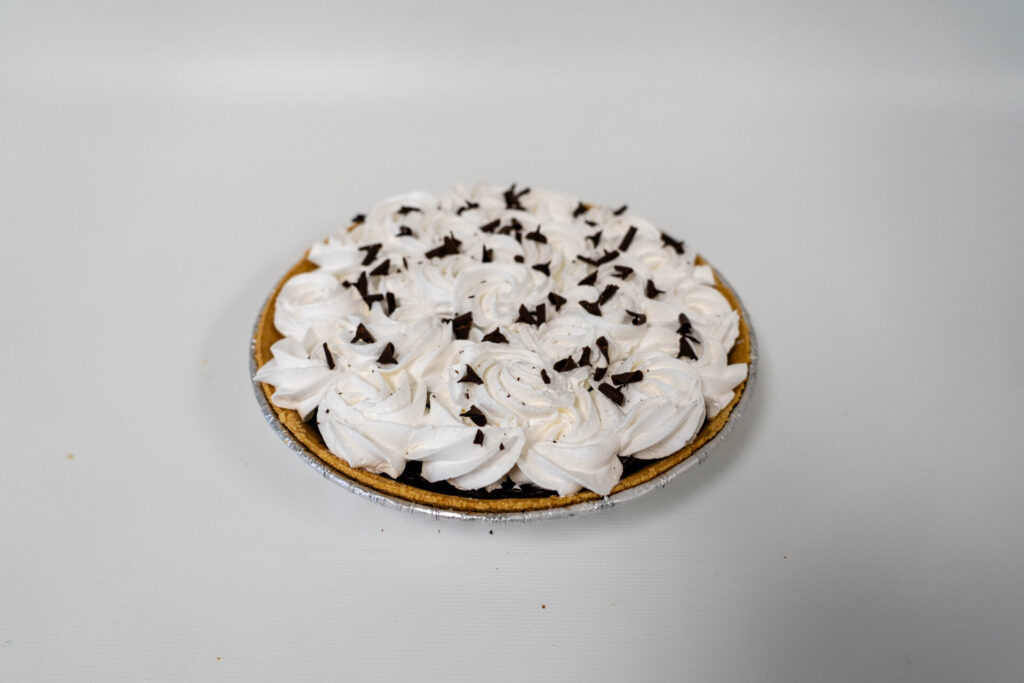French Silk Pie with a smooth, creamy chocolate filling in a flaky pie crust, topped with whipped cream and chocolate shavings.