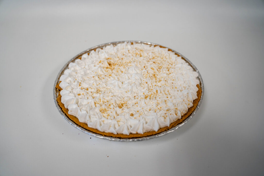 Key Lime Pie with a smooth, tangy lime filling in a graham cracker crust, topped with whipped cream and fresh lime zest.