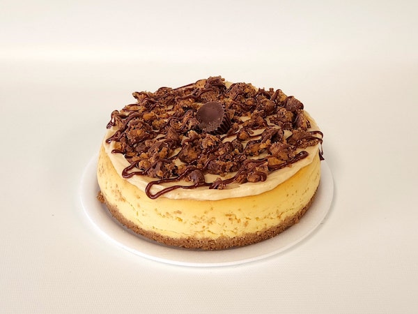 Peanut Butter Mini Cheesecake with a rich, creamy peanut butter filling on a chocolate cookie crust, topped with a drizzle of chocolate.