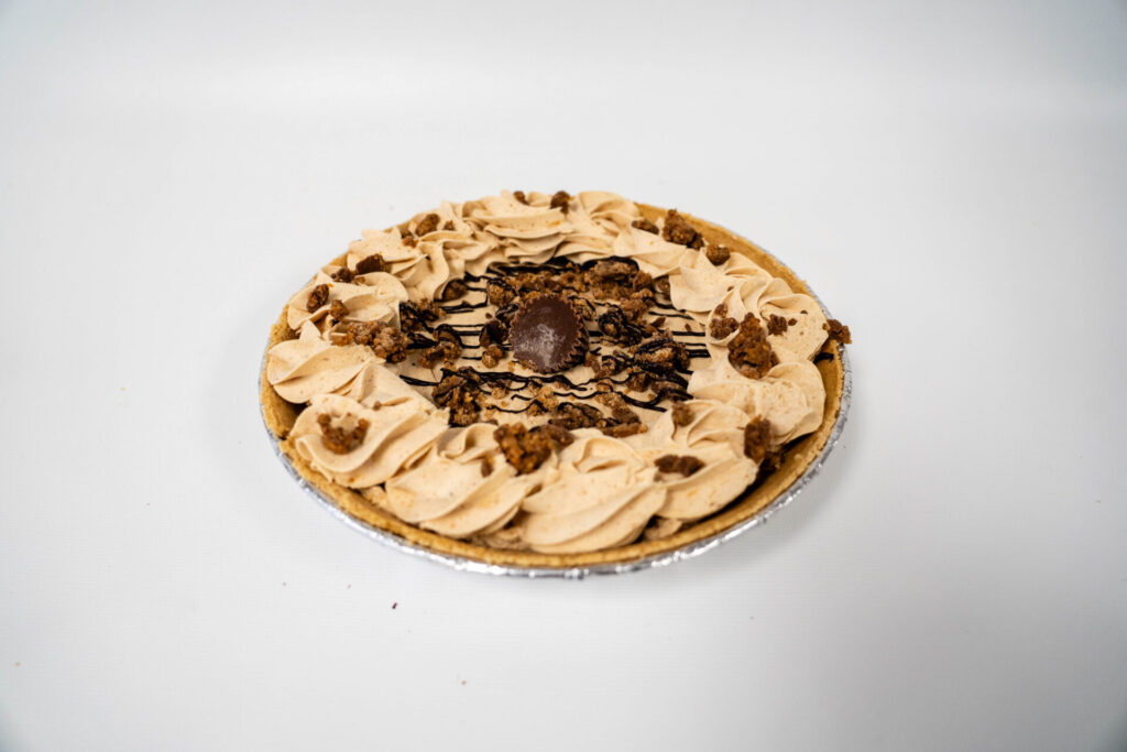 Peanut Butter Pie with a creamy, smooth peanut butter filling in a graham cracker crust, topped with whipped cream and chocolate drizzle.
