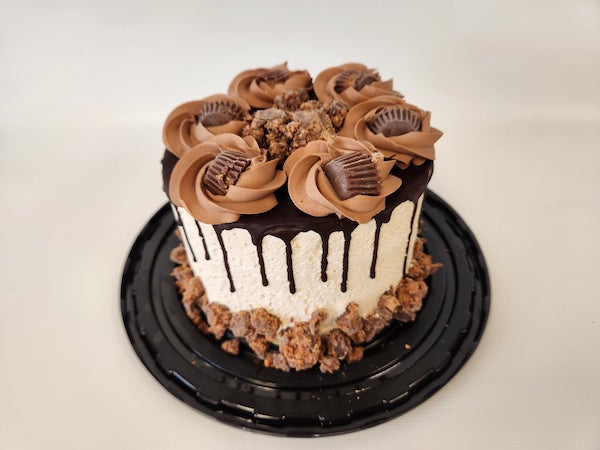 Peanut Butter Whipped Cream Torte with layers of light, fluffy whipped cream and rich peanut butter filling, topped with chocolate drizzle and decorative swirls.