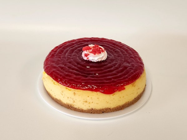 Mini Raspberry Cheesecake with a smooth, creamy filling on a graham cracker crust, topped with vibrant raspberry sauce and a fresh raspberry.