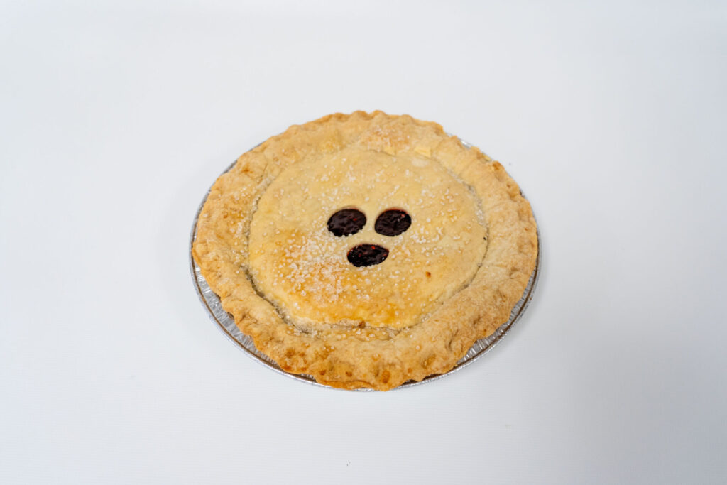 Raspberry Pie with a golden, smooth top crust and vibrant red raspberry filling visible through vented slits.